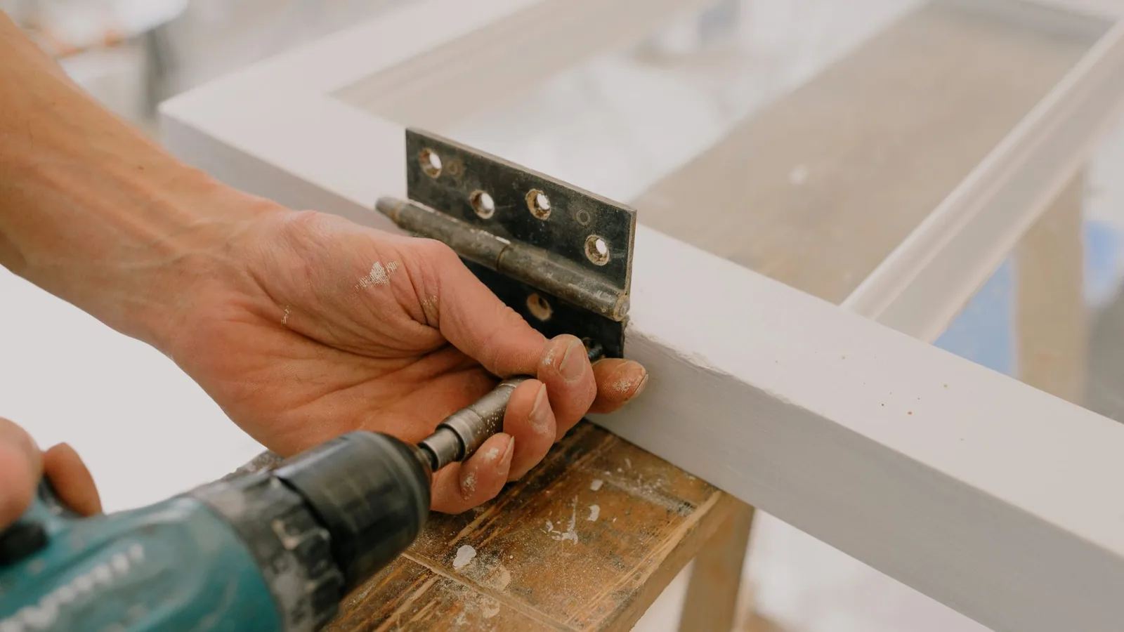 Menuisier fixant une paumelle sur un châssis de fenêtre en bois